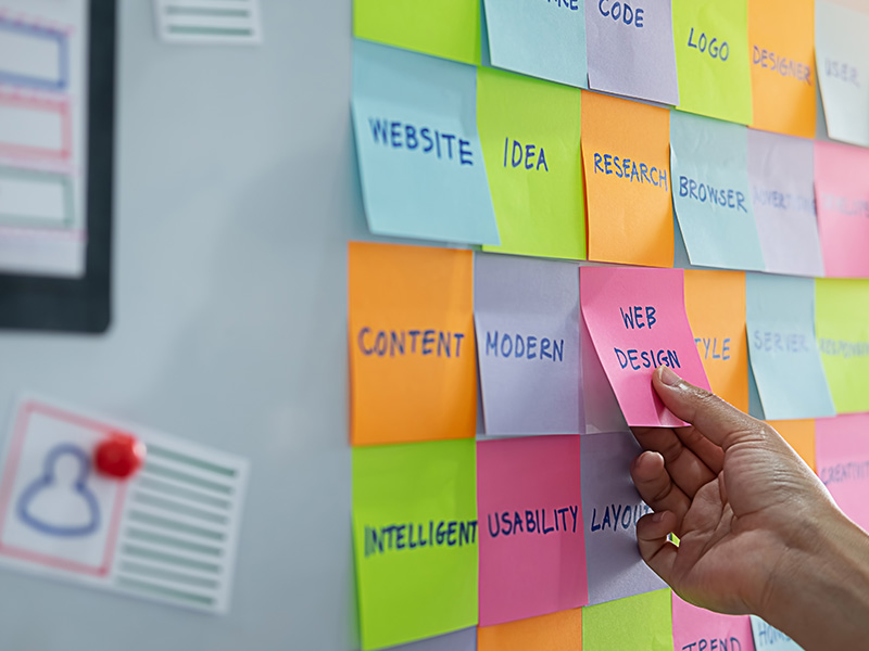 A modern office workspace featuring a storyboard displaying a website design mockup, surrounded by notes and design tools.